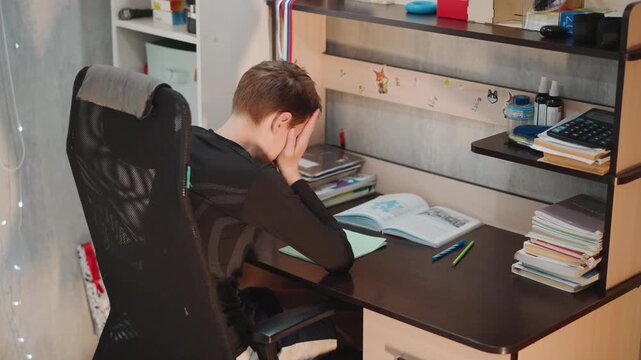 Child faces stress. Grandson anxious over studies. Young boy overwhelmed during homework time. Young student exhausted and tense while attempting to complete his schoolwork and prepare for exams