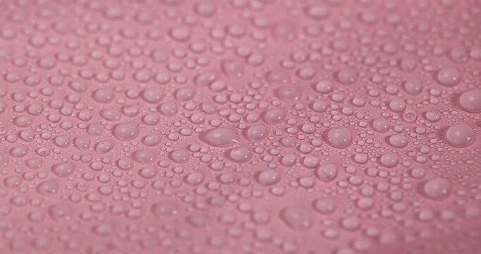 wet pink smooth plastic for wrapping gifts and bouquets, covered with water droplets smooth pink synthetic material, color image