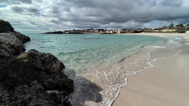 Contrasti di grigio e azzurro sulla spiaggia ionica a Marina di Pulsano, con il cielo nuvoloso - Salento, Puglia, Italia