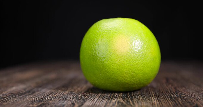 a yellow-green grapefruit on the table, one large grapefruit with a peel of different colors, unripe grapefruit