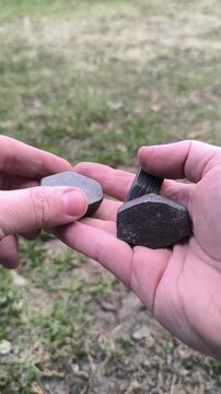 Close up of hands turning and inspecting old lead fishing weights outdoors