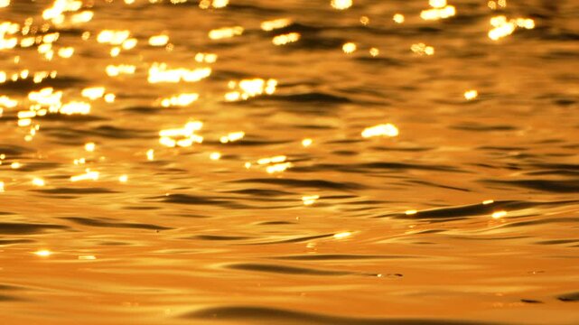 Golden water sunset reflecting sunlight on calm ocean waves creating a serene and warm atmosphere at twilight