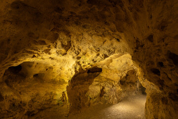 Obraz premium illuminated cave interior with rock formations and tunnel