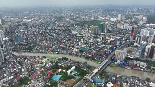 Manila cityscape at river banks aerial. Downtown area with cottages, skyscrapers, buildings. Urban Philippines city scape with streets and roads. Town drone shot. Poor Homes Along Rich Skyscrapers.