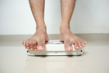 Fototapeta premium Man's Feet Standing on Weighing Scale