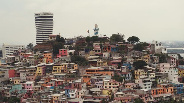A panoramic view of the colorful houses and architecture of Las Pe&ntilde;as in Guayaquil, Ecuador, with a lighthouse and a tall building in the background