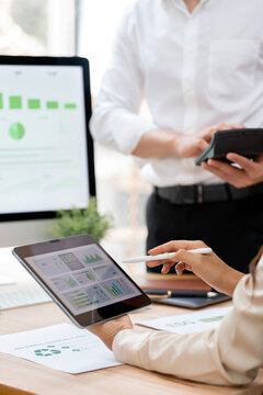 Business professionals analyzing sustainable energy data and ESG financial reports using tablet and calculator in office.