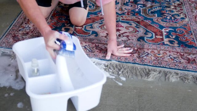 Close up on woman's hands scrubbing oriental rug fringe with sudsy brush