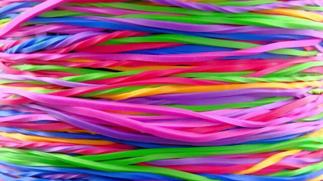 a dense, chaotic tangle of colorful intertwined elastic rubber bands in trails fast motion