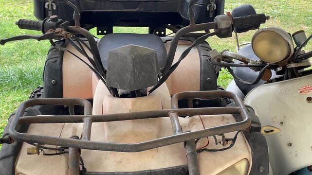 ATVs parked on green grass, highlighting handlebars and seats, suitable for adventure themes