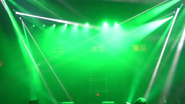 Bright green spotlights cut through the dark atmosphere of an empty stage or venue. The dynamic beams create circular patterns on the floor, evoking an energetic mood for a concert or live event.

