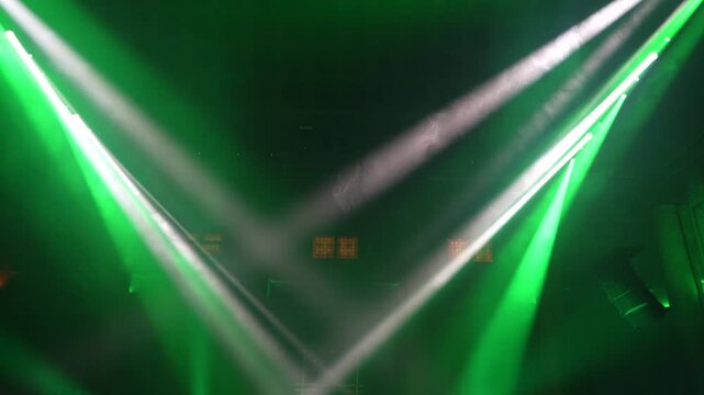 Bright green spotlights cut through the dark atmosphere of an empty stage or venue. The dynamic beams create circular patterns on the floor, evoking an energetic mood for a concert or live event.
