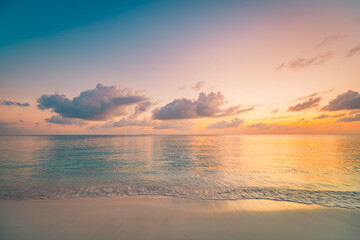 Obraz premium Radiant tropical beach at sunset with colorful sky and soft clouds, calm ocean waves, peaceful dreamy nature landscape background for summer travel and relaxation