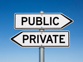 Fototapeta premium A signpost with public and private signs pointing in opposite directions against a clear blue sky