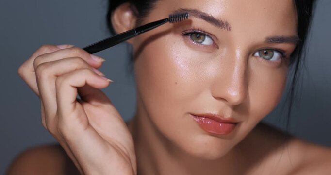 Close-Up Woman Applying Eyebrow Makeup with Brush in Studio
