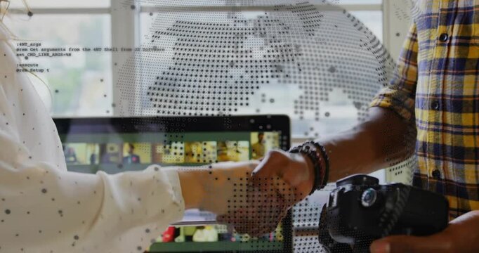 Woman showing tablet while man holding camera extending hand, sealing deal as dotted globe appears