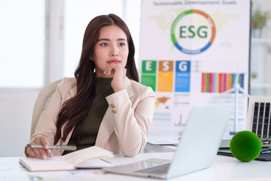 Asian adult business woman planning sustainable ESG strategy developing corporate responsibility goals professional office workspace considering environmental social governance future
