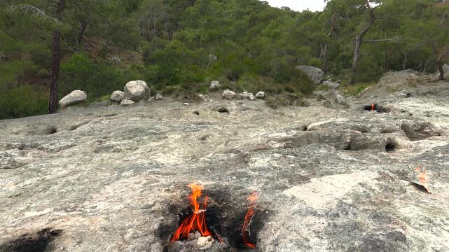 Yanartas methane flames burn through rocky vents at Cirali Antalya Turkey as eternal fire. Natural gas seepage creates a geological phenomenon with burning stone, fumarole heat, scientific interest.
