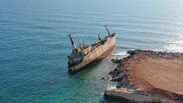 Edro III cargo ship remains partially submerged and rusty on shallow coastal waters near Sea Caves in Paphos, Cyprus, a significant monument, power of sea and human resilience. Aerial view drone shot