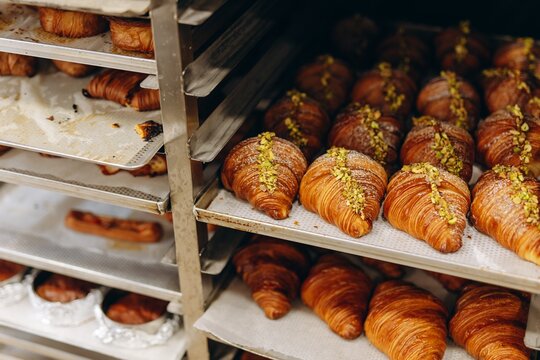 Fresh pistachio-topped croissants on bakery racks ready for morning service in an artisan patisserie