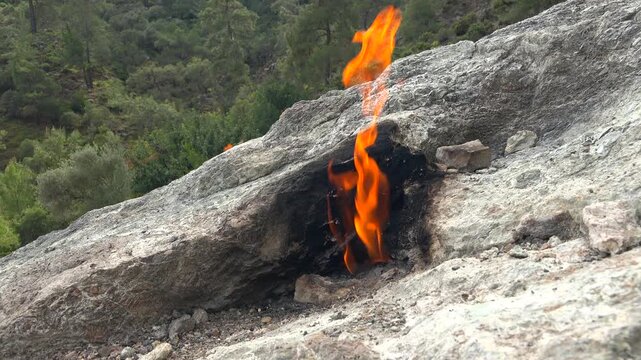 Yanartas methane flames burn through rocky vents at Cirali Antalya Turkey as eternal fire. Natural gas seepage creates a geological phenomenon with burning stone, fumarole heat, scientific interest.
