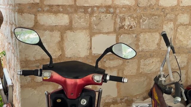 Motorbike handlebars and mirrors against a rustic stone wall background