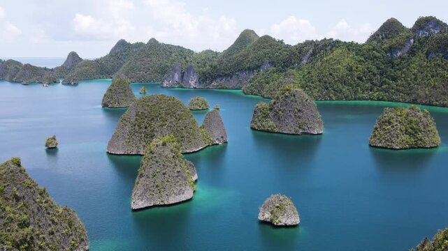Drone Approaching Lush Green Karst Islands in Turquoise Lagoon of Wayag archipelago, Raja Ampat, Indonesia.