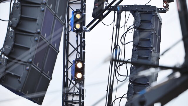 Large format sound system speakers and stage lights hanging from a metal truss structure