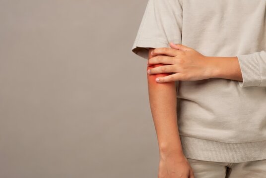 Person touching irritated elbow against a neutral background, skincare and body care concept showing dry skin discomfort, wellness concern, minimal composition, and soft copy space.