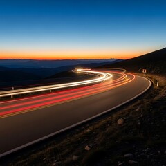 Obraz premium Nighttime highway curves with car light trails and beautiful sunset.