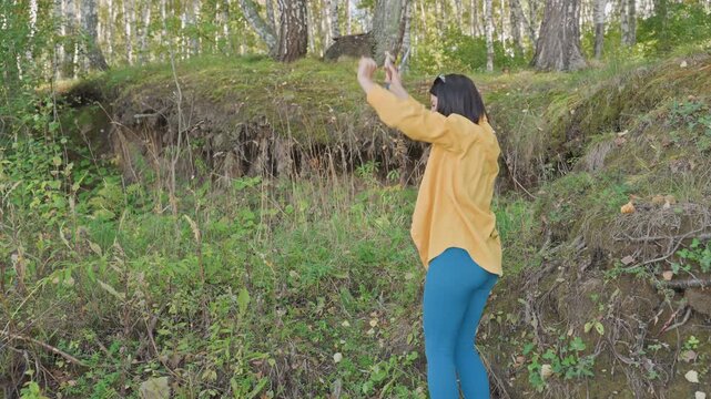 Woman celebrates mushroom find with phone camera, caucasian camper at campsite lifts arms and captures joyful moments, bright outdoor greens, triumphant smile and eager sharing vibe
