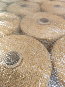 Multiple spools of brown craft string secured together under transparent protective packaging material