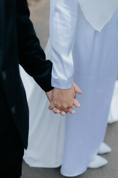 Pasangan pengantin pria dan pengantin perempuan saling memegang tangan sebagai simbol cinta dan kerja sama dalam sebuah pernikahan yang penuh kesuksesan bersama rakyat