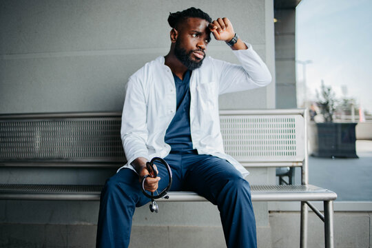 Tired medical worker sitting in front of the hospital