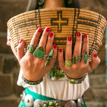 Woman holding woven basket wearing turquoise jewelry