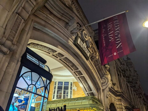 Ornate stone archway and red holiday banner at the entrance of historic Burlington Arcade in London