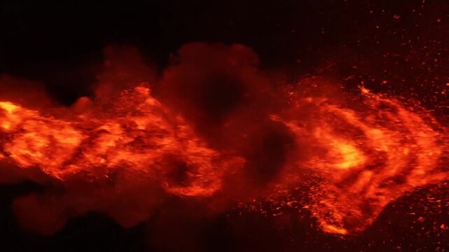 Vibrant orange and red flames spreading across a dark background with glowing embers and sparks.