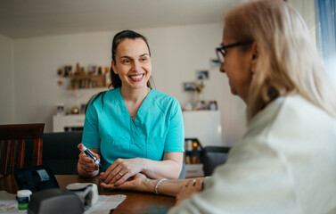 Fototapeta premium Doctor checks senior woman's blood sugar at home