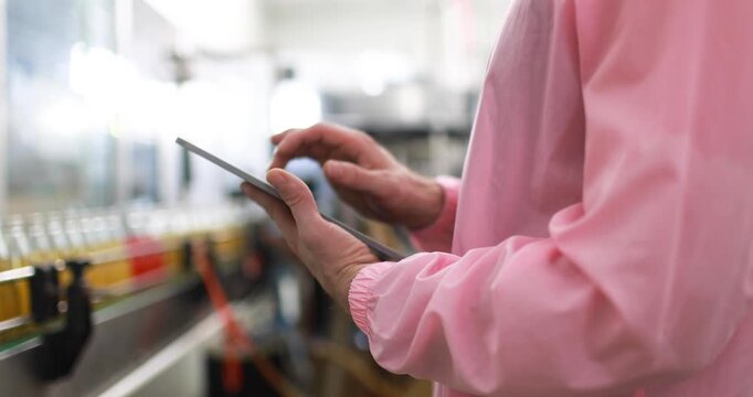 Factory worker inspecting production line tanker in of fruit juice beverage product factory or drinking water manufacturing  with computer tablet.