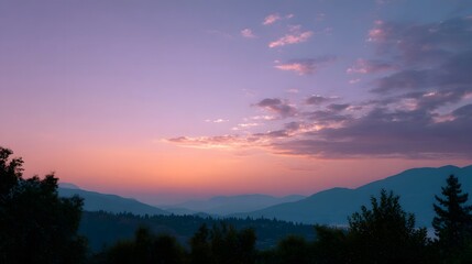 Obraz premium Serene mountain vista at twilight with a soft gradient of sunset colors in the sky and atmospheric haze over distant peaks