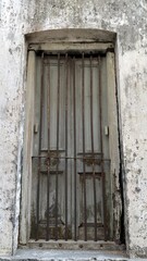 Obraz premium This image features an old wooden window secured with rusted metal bars in a distressed wall