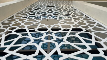 Obraz premium Extensive White Geometric Pattern Screen on a Building Facade with Reflective Windows