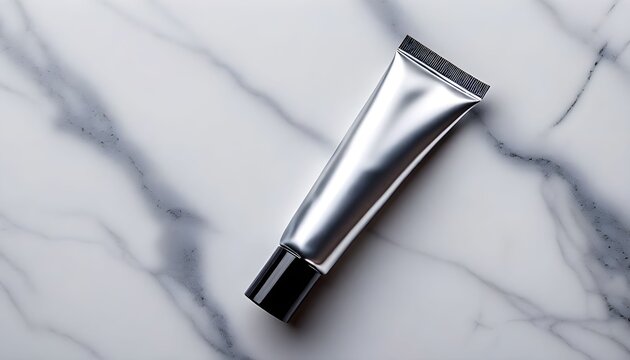 A silver tube lies on a white marble surface with grey veins.