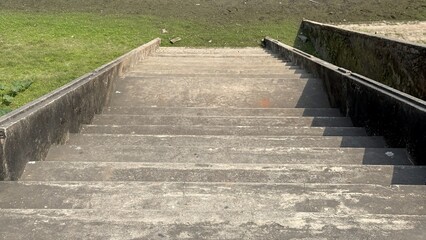 Obraz premium Weathered Concrete Steps Descending Towards a Grassy Embankment and Muddy Shore