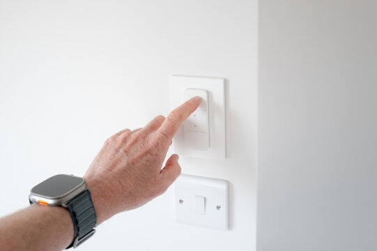Homeowner seen pushing a wireless, internet of things remote light switch within a loft conversion. The light intensity as well as the hues can be controlled.