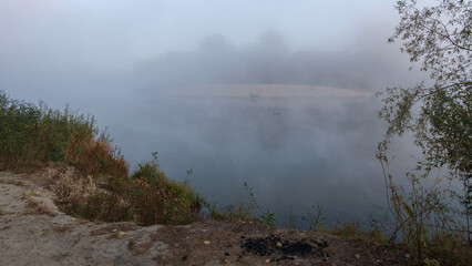 A tranquil river scene with dense fog rolling over the water and surrounding vegetation © Александр Арендарь