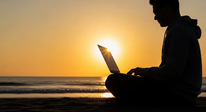 Silhouette of a remote worker using a laptop on a beach at sunset, enjoying freedom and productivity outdoors