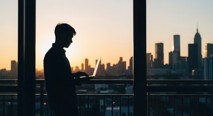 Fototapeta premium Man Silhouette Using Laptop Against Sunset Cityscape View From Balcony