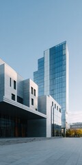 Obraz premium Modern glass office tower and concrete civic building with open plaza under clear blue sky urban architecture and minimalist facade