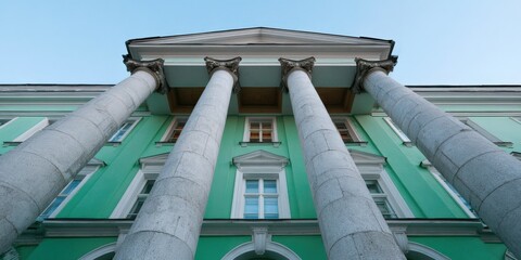 Fototapeta premium Turquoise neoclassical building with white columns, arched windows, towering portico and dramatic low angle perspective of mint green facade